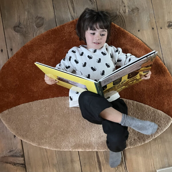 Girl reading on Castagnona tufted rug