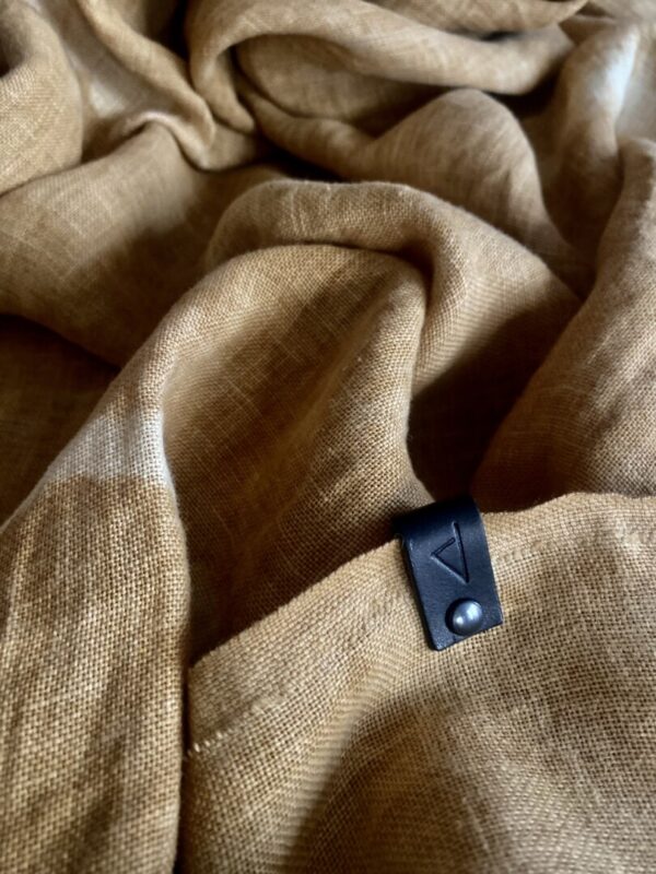 Ricciu Davia Tintura Vegetale stole. 100% French linen hand-dyed from bogues harvested in Orezza. Photo of the stole flat. Photo zoom on the leather label.